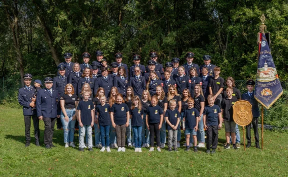 Gruppenbild vieler aktiver und passiver Mitglieder in Uniform vor einem Wald